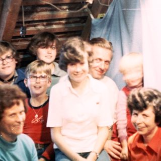 Group of people posing indoors on wooden stairs.