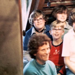 Group of people posing indoors on wooden stairs.