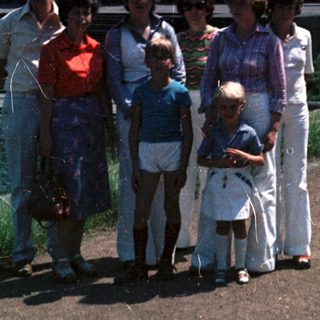 Family group photo near waterfront in outdoor setting.