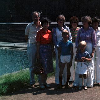 Family group photo near waterfront in outdoor setting.