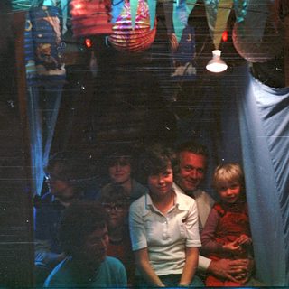 Family group posing indoors with dim lighting.