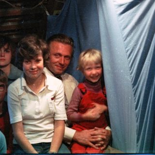 Family group photo in a rustic indoor setting.