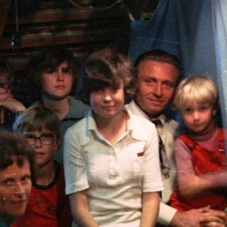 Family group posing indoors with festive lights.