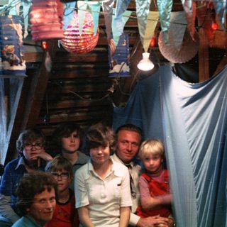 Family group posing indoors with festive lights.