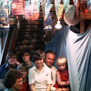 Family gathering at festive indoor event with decorative lights.