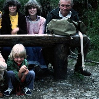 Family group photo outdoors on wooden bench.
