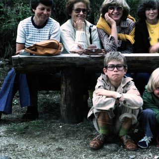 Family group photo outdoors on wooden bench.