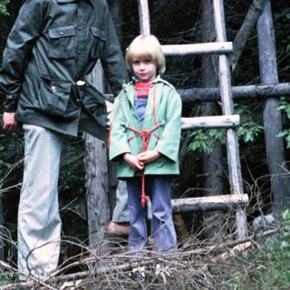 A man and two children near a wooden observation tower.