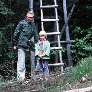 A man and two children near a wooden observation tower.