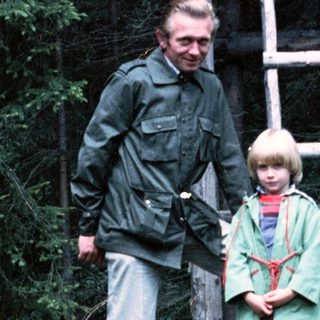 A man and two children near a wooden observation tower.