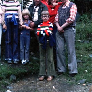 Family group photo at Vitáme Vás signpost in forest.