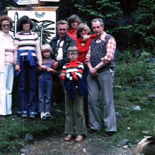 Family group photo at Vitáme Vás signpost in forest.