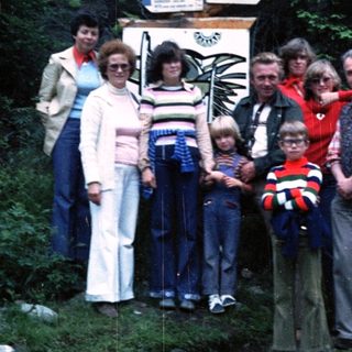 Family group photo at Vitáme Vás signpost in forest.