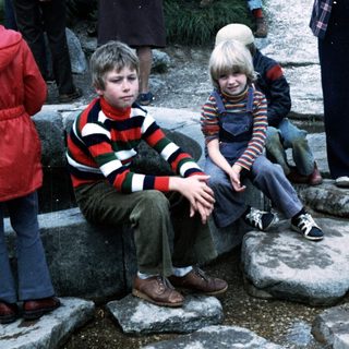 Two children sitting on rocks outdoors during an event.
