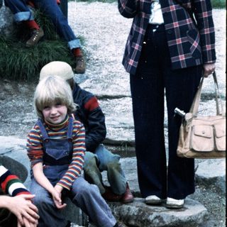 Two children sitting on rocks outdoors during an event.