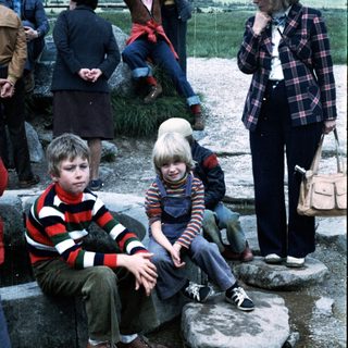 Two children sitting on rocks outdoors during an event.