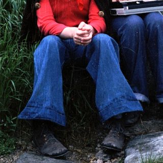 Three people sitting outdoors on rocks, holding a laptop.