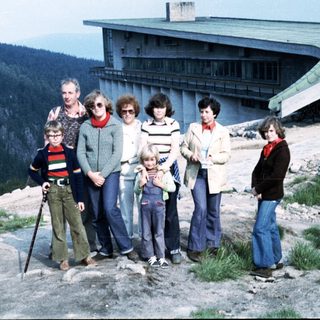 Family group posing outdoors near mountain lodge.