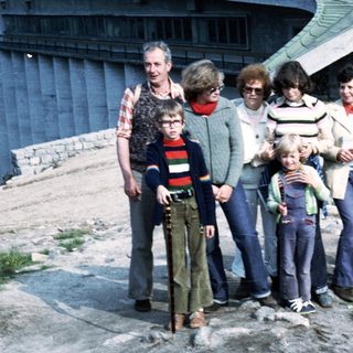 Group of seven people posing outdoors near a building.
