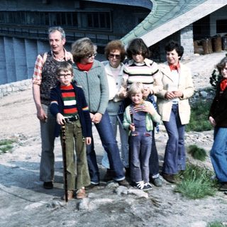 Group of seven people posing outdoors near a building.