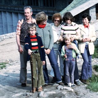 Group of seven people posing outdoors near a building.