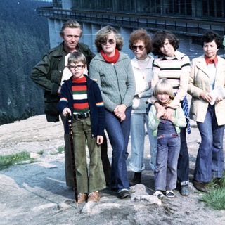 Family group posing outdoors near mountain resort.