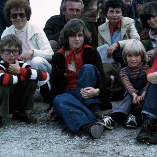 Family group posing outdoors in 1980s-style clothing.