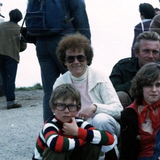 Family group posing outdoors in 1980s-style clothing.
