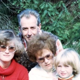 Family group photo outdoors in forest setting.