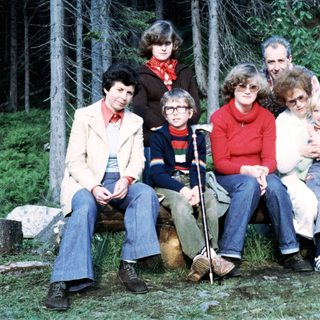 Family group photo outdoors in forest setting.