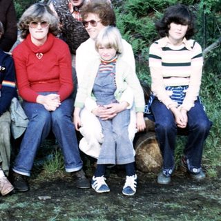 Group of eight people posing outdoors in forest setting.