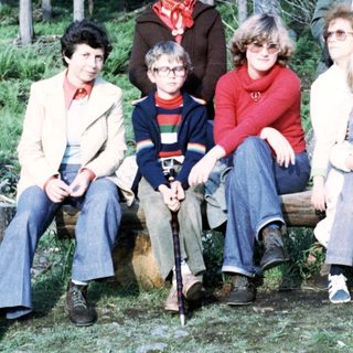 Group of people posing outdoors in forest, 1970s.