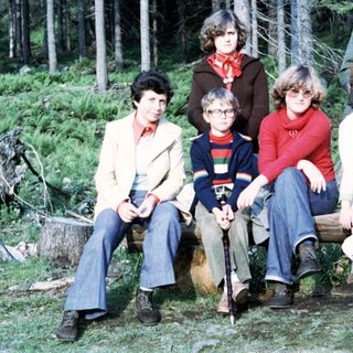 Group of people posing outdoors in forest, 1970s.