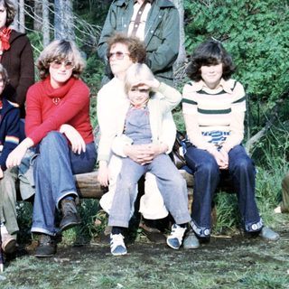 Group of people posing outdoors in forest, 1970s.