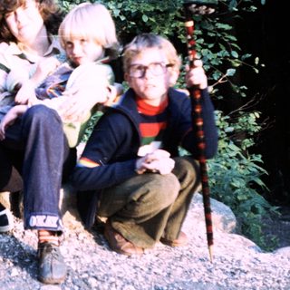 Five people posing together outdoors in a wooded area.