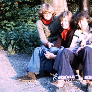 Five people posing together outdoors in a wooded area.