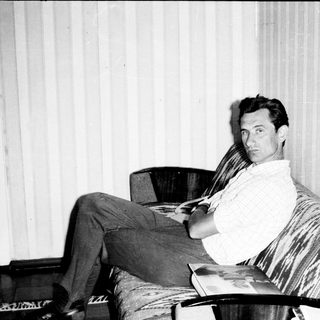 Man reading newspaper in relaxed indoor setting.