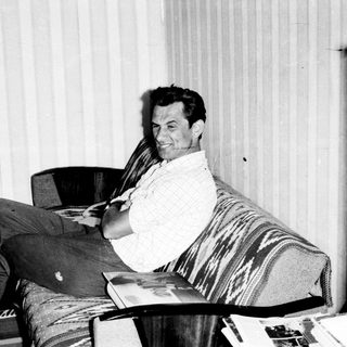 Man relaxing in armchair with scarf, reading.