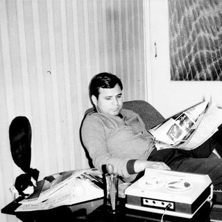 Man reading newspaper in relaxed indoor setting.