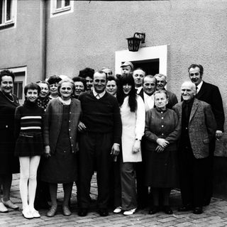Group of people posing together outdoors in 1960s attire.