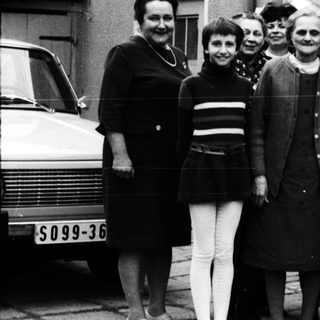 Group of people posing together outdoors in 1960s attire.