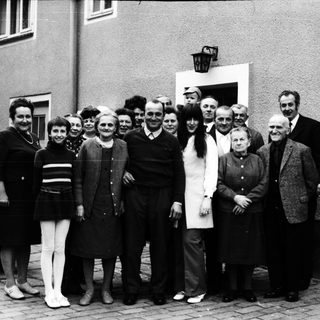 Group of people posing together outdoors in 1960s attire.