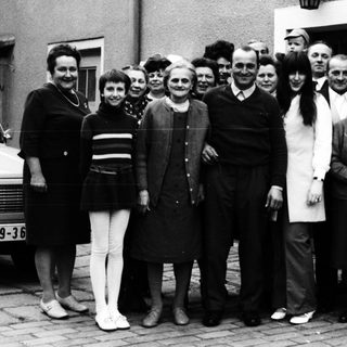 Group of people posing together outdoors in 1960s attire.