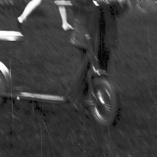 Blurred reflection of person riding scooter.