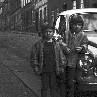 Two boys posing with vintage car.