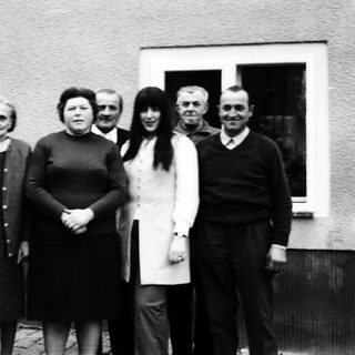 Group of people posing outdoors in front of a house.