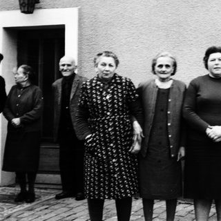 Group of people posing outdoors in front of a house.
