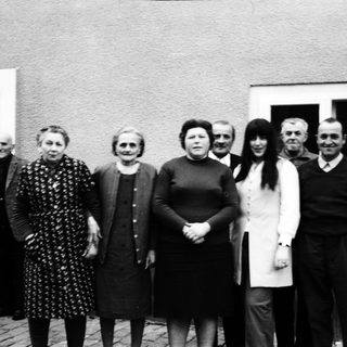 Group of people posing outdoors in front of a house.