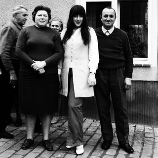 Family group posing outdoors near a house.