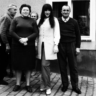 Family group posing outdoors near a house.